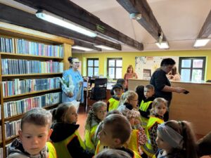 Dzieci odwiedzają bibliotekę w tle widać pracowników, okna oraz książki