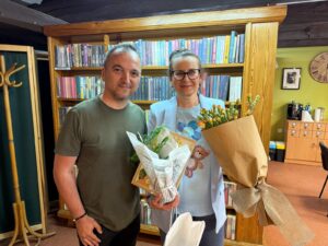 Kobieta i mężczyzna trzymają kwiaty na tle książek